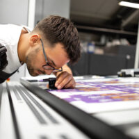 Worker checking print quality of graphics in modern printing house.